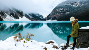 Une femme se tient près du lac Louise et regarde le lac en hiver.