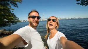 Deux personnes prenant un selfie avec la vue du centre-ville de Toronto en arrière-plan.