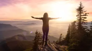 Femme adulte caucasienne aventureuse faisant de la randonnée dans la nature canadienne avec les mains ouvertes dans un paysage montagneux. Rendu artistique du ciel au coucher du soleil. Chilliwack, à l'est de Vancouver, Colombie-Britannique, Canada.