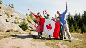 Family with large Canadian flag celebration in mountains.