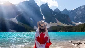 Personne avec un drapeau canadien autour d’elle, debout près du lac
