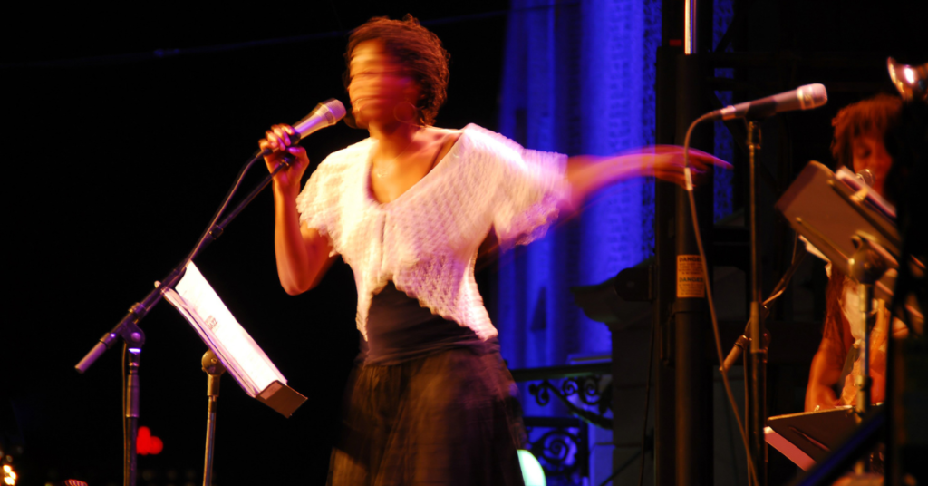 Image of a female singer in motion on stage at the Harvest Jazz & Blues Festival in Fredericton, captured with a blurred motion effect to convey energy and live performance excitement.